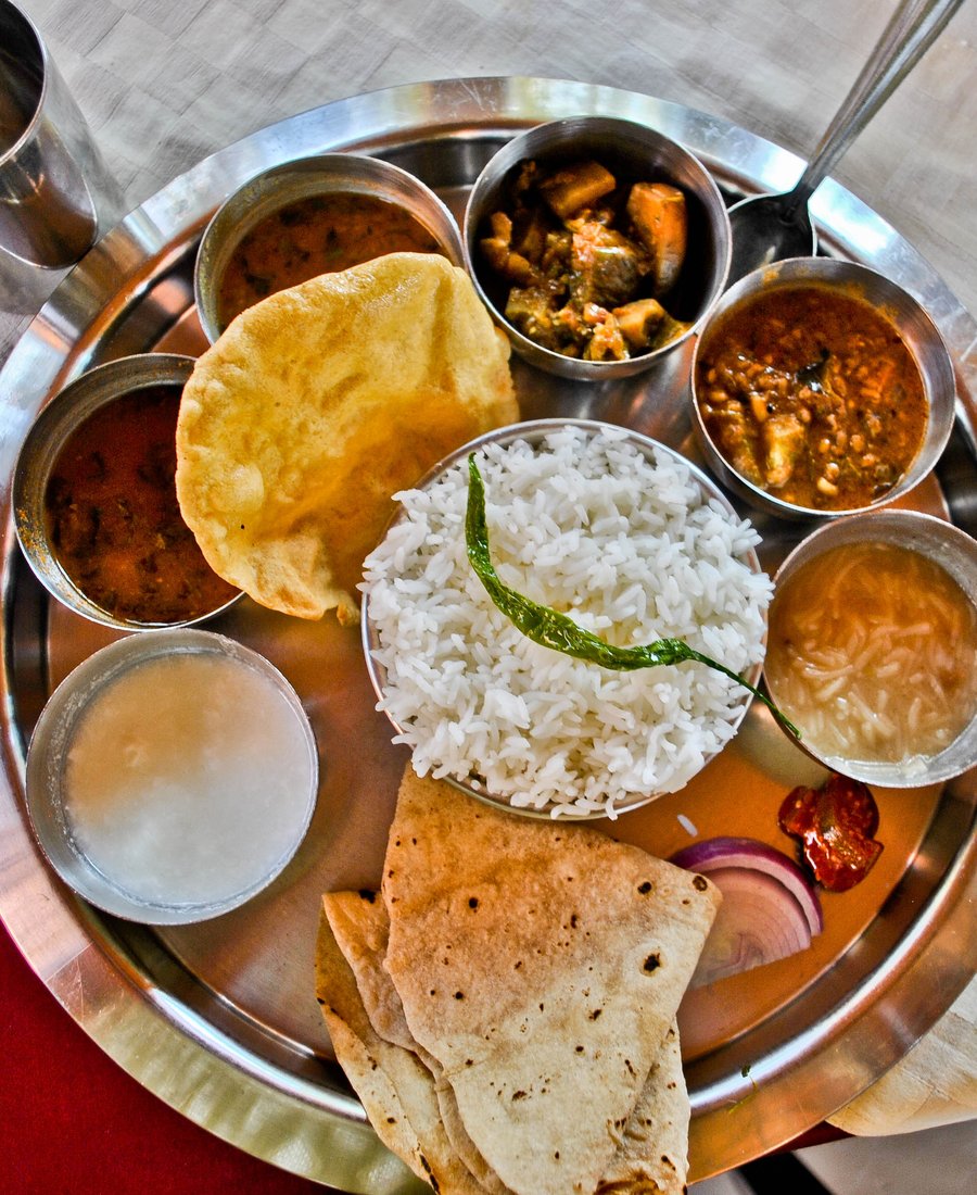 A veg thali with soft chapatis, papad, rice, dal, sabzis, curd, pickle and onion